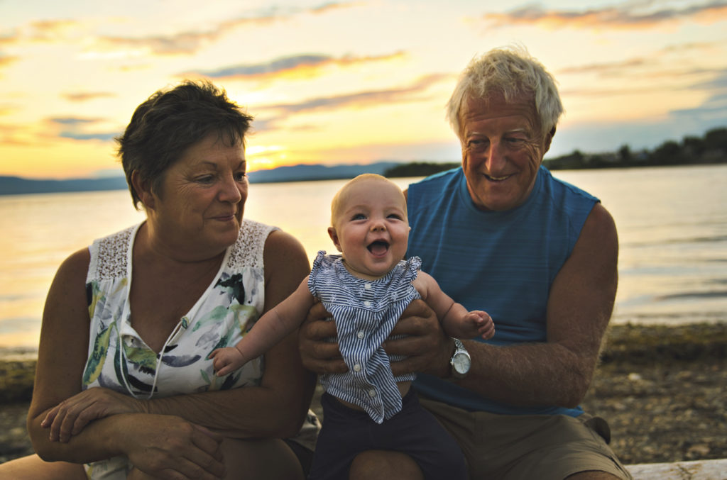 The nice grandparents playing with their baby granddaughter on the beach