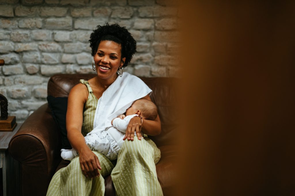 Black mom breastfeeding baby on couch