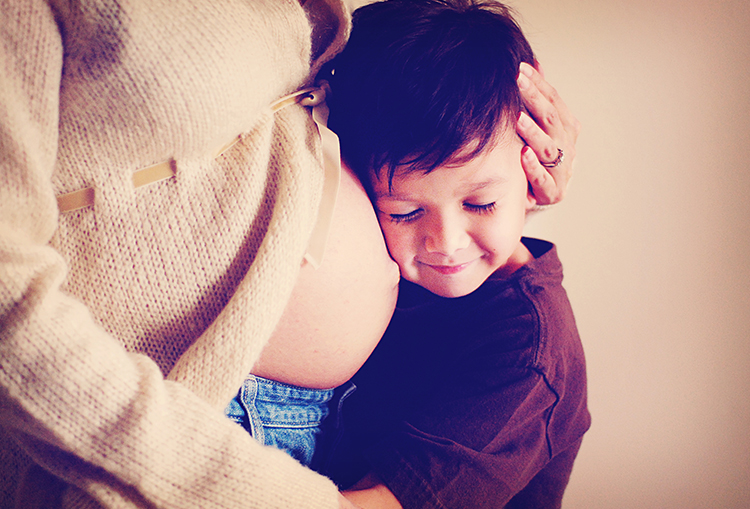 Pregnant Woman Hugs Toddler Against Belly